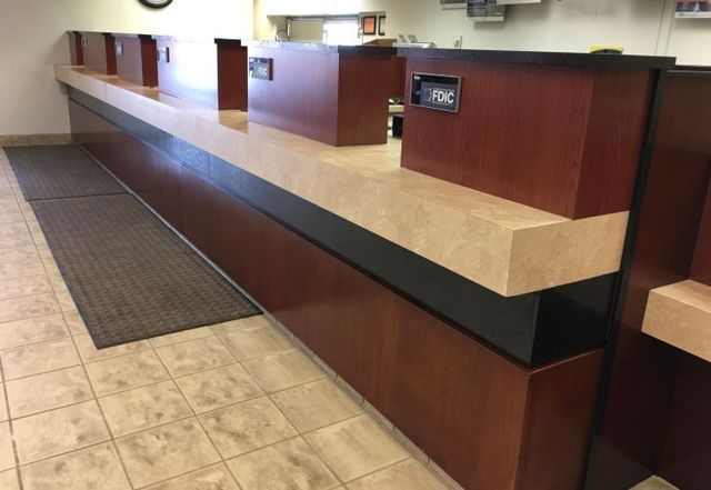 A long wooden counter in a bank with a black trim