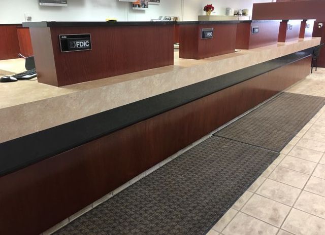A long wooden counter in a bank with a sign that says pdc