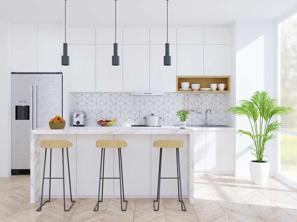 A Modern Kitchen With White Cabinets, Stools, A Refrigerator And A Plant — Gold Coast City Plumbing In Helensvale, QLD