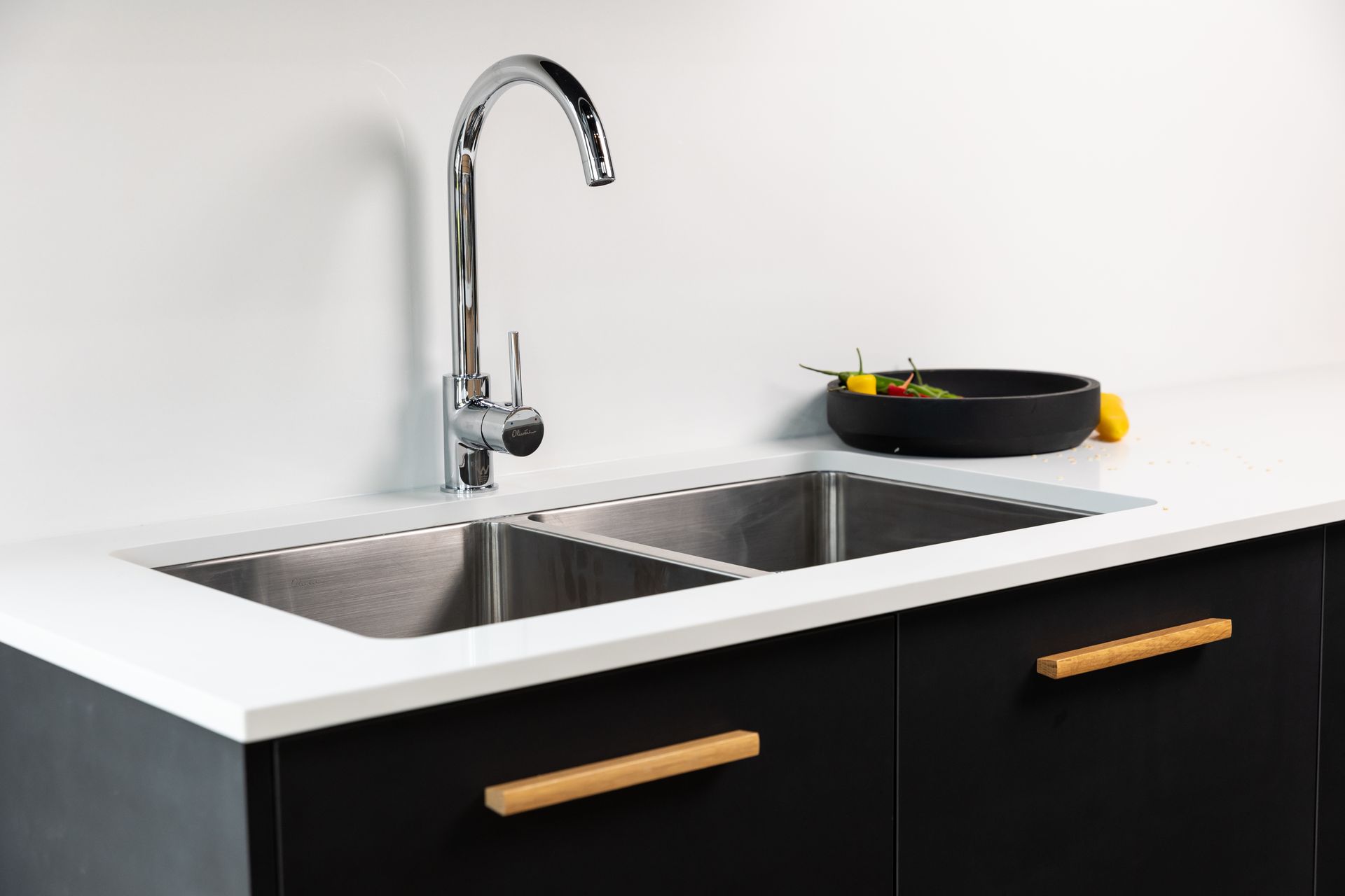 A kitchen sink with a faucet and a bowl of lemons on the counter.
