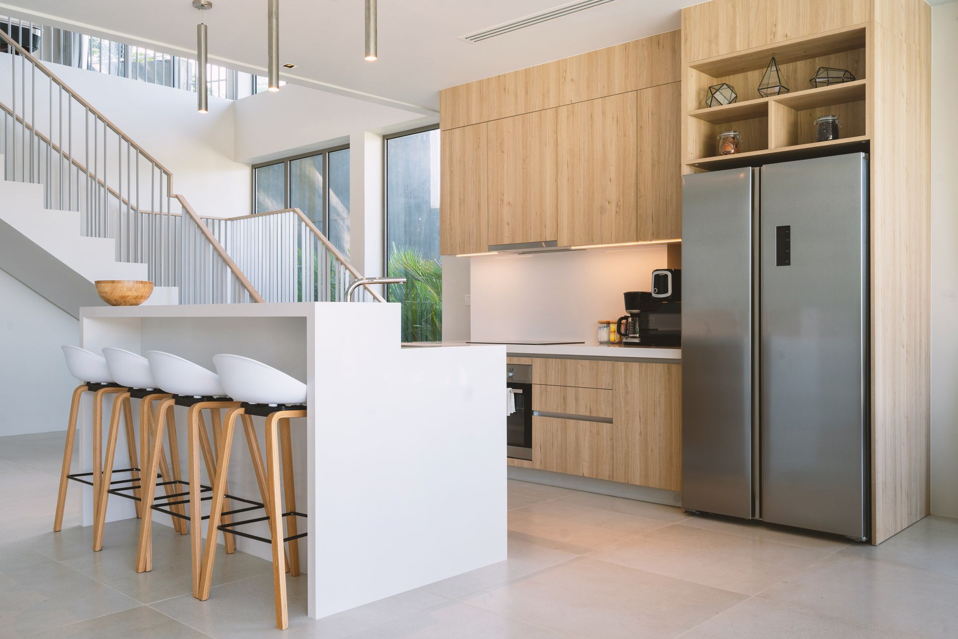 A kitchen with wooden cabinets , stainless steel appliances , a refrigerator and a staircase. — Better Stone in Caloundra West, QLD