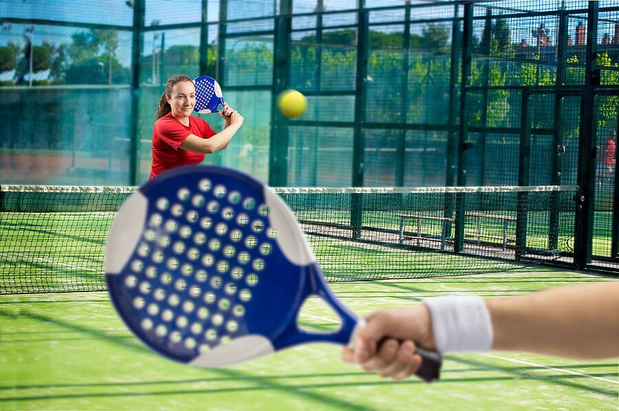 A woman in a red shirt is playing paddle tennis