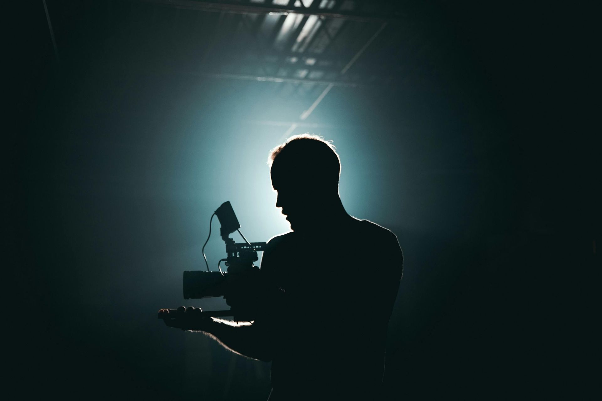 A silhouette of a man holding a camera in a dark room