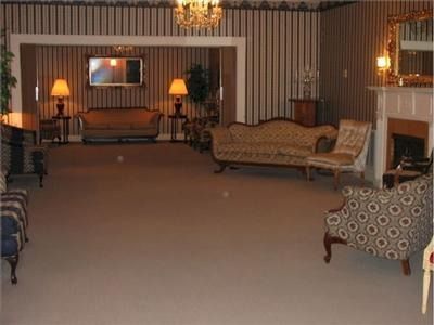 Funeral home interior with couches, fireplace, and ornate chandelier.