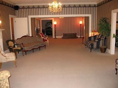 Formal room with couches, carpet, and ornate wallpaper. A chandelier hangs from the ceiling.