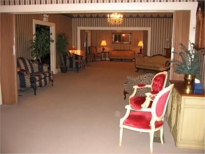 Funeral home interior with seating, including red velvet chairs, and patterned walls.