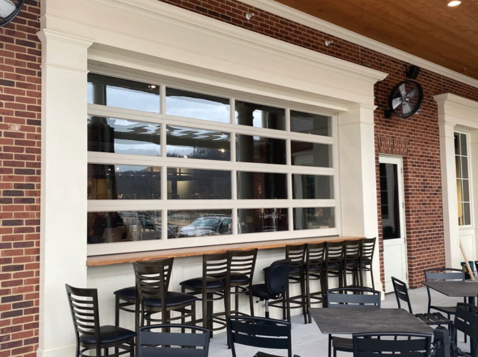 Outdoor patio with a glass garage door, bar seating, and brick building.