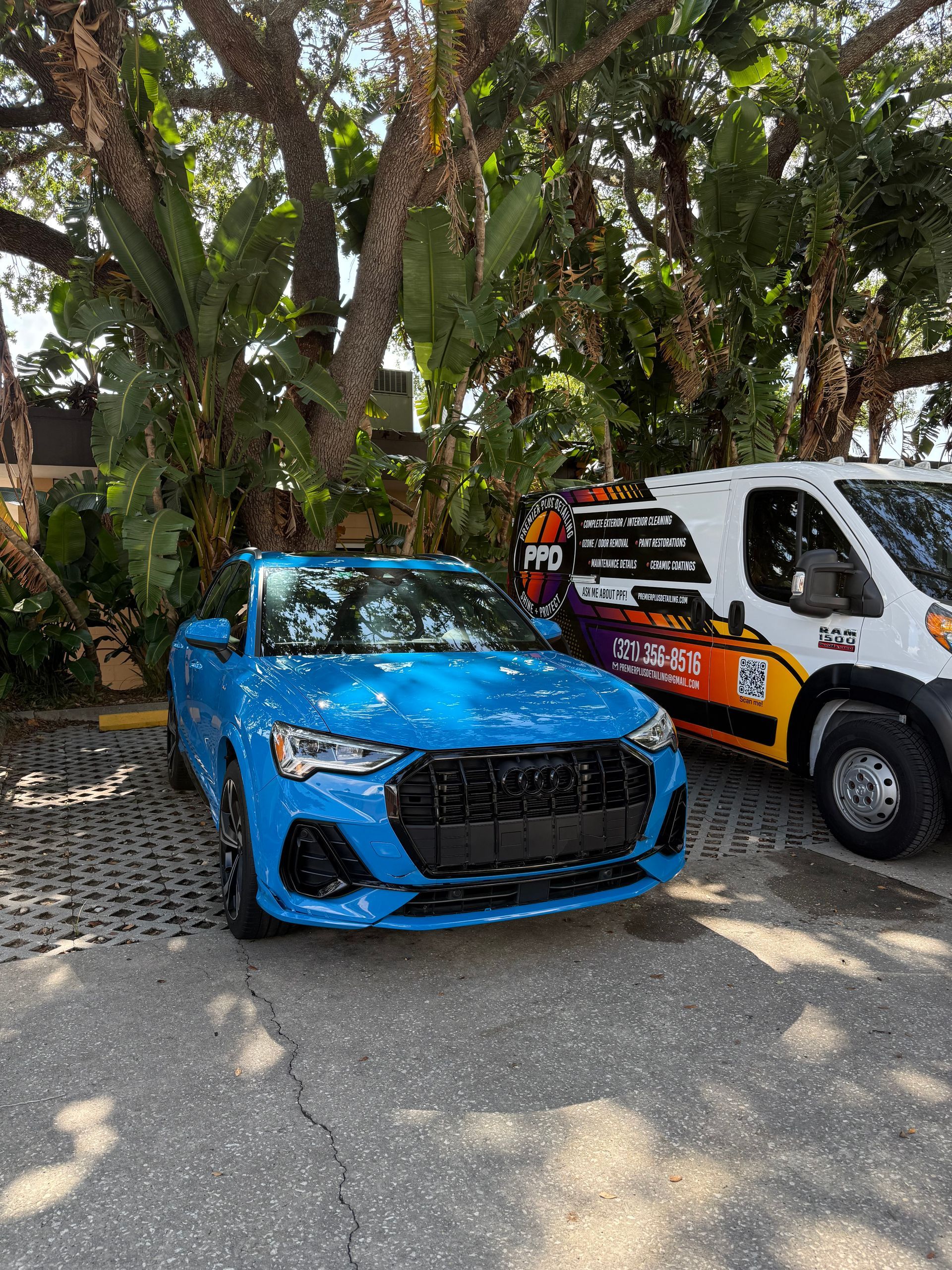 A blue car is parked next to a white van in a parking lot.