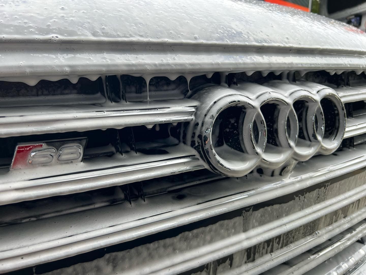 A close up of an audi grille covered in foam.