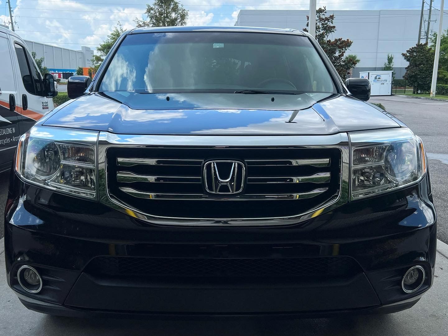 A black honda ridgeline is parked in a parking lot.