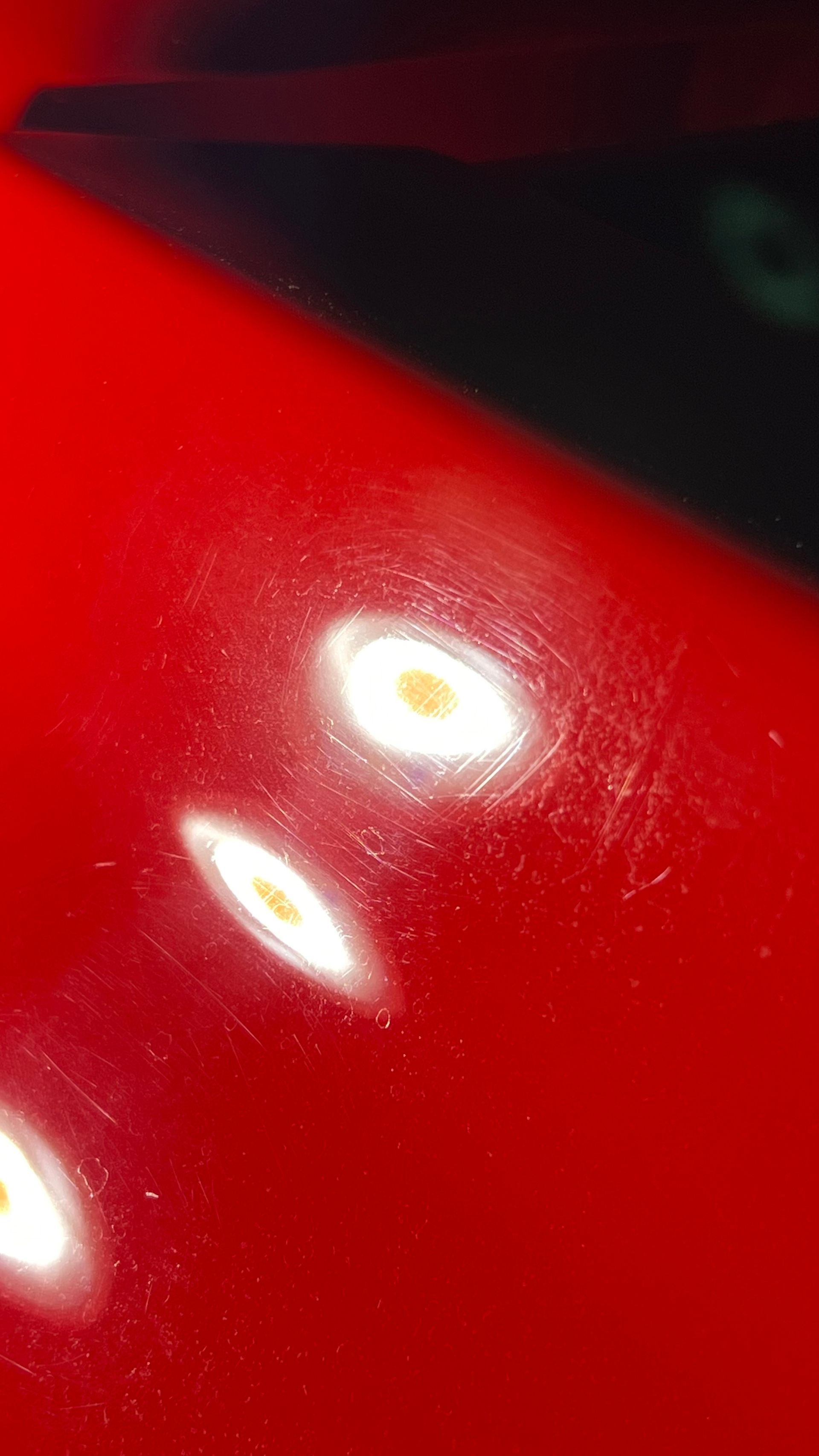 A close up of a red car with white spots on it.