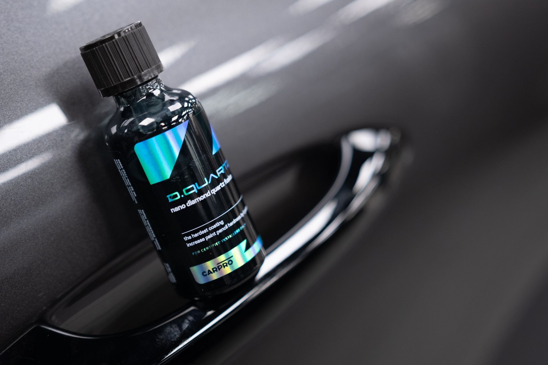 A bottle of polish is sitting on the door handle of a car.