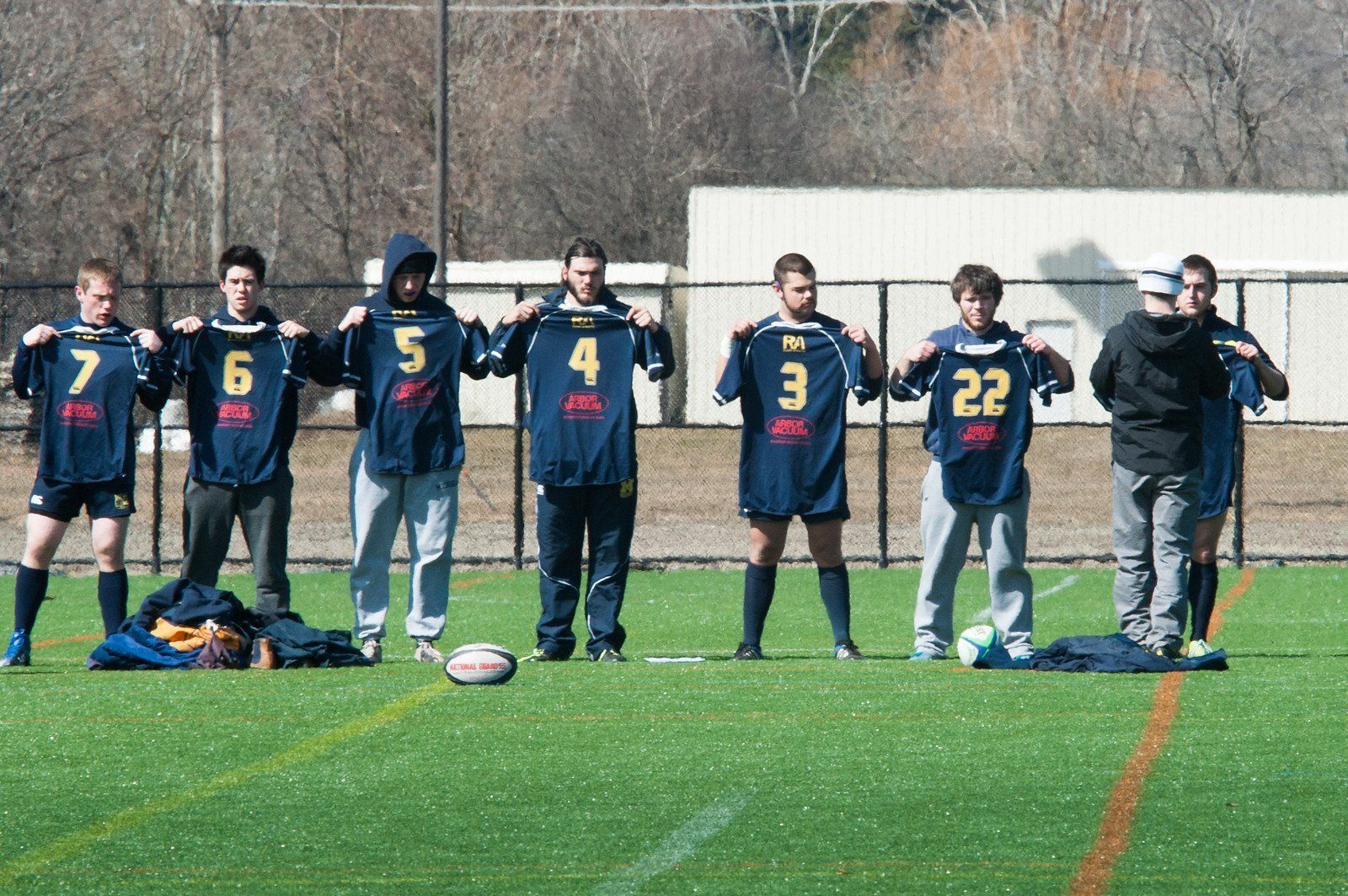 A group of soccer players standing on a field holding up their jerseys