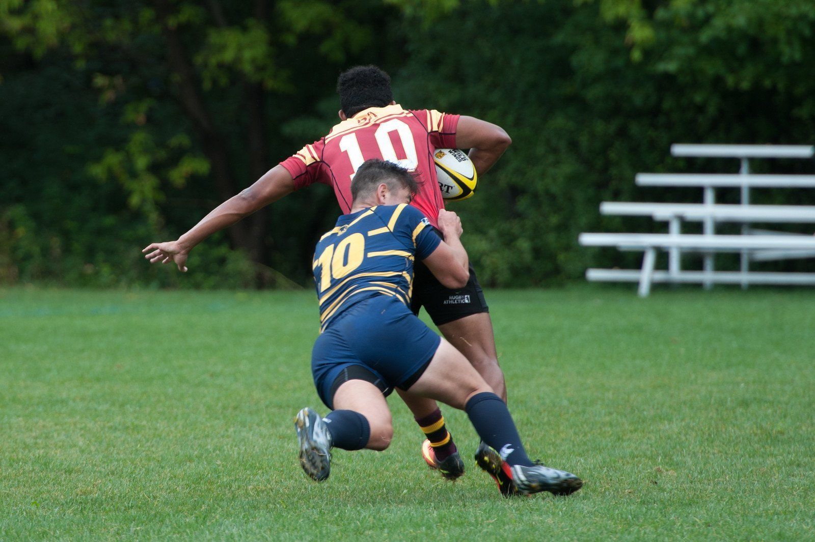 A rugby player with the number 10 on his back is being tackled by another player.