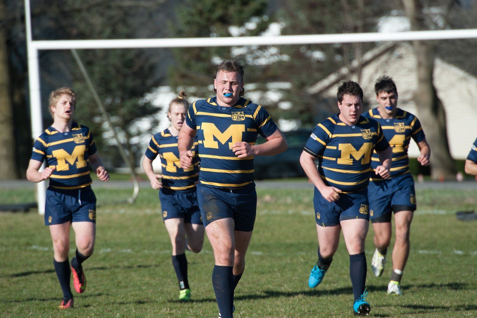 A group of rugby players wearing blue and yellow uniforms with the letter m on them