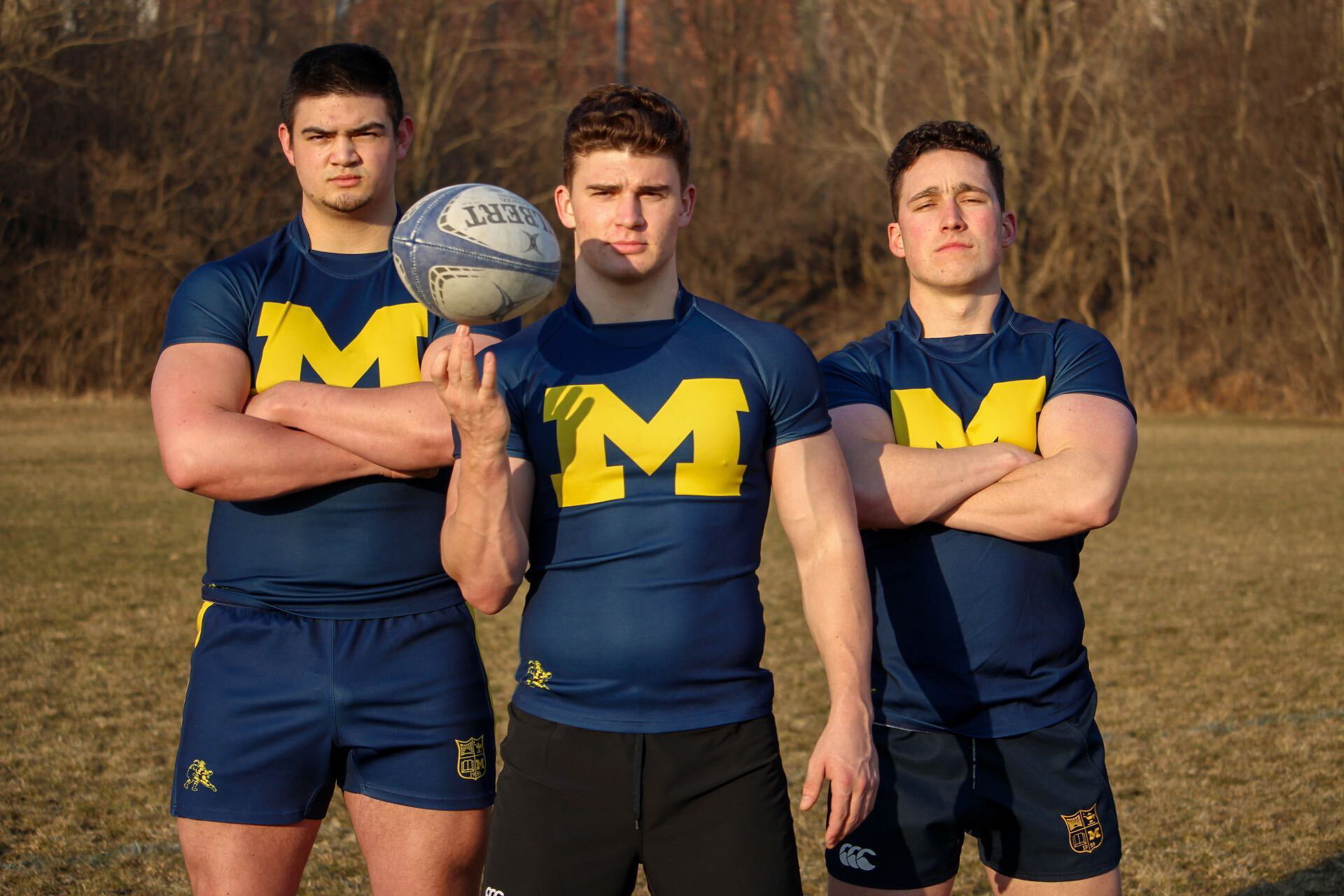 Three men wearing blue shirts with the letter m on them