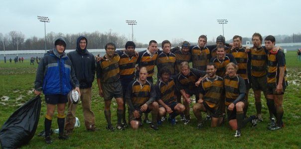 A group of rugby players are posing for a picture on a field.