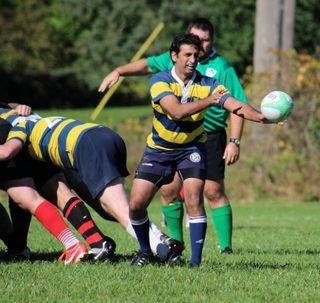 A man in a yellow and blue striped shirt is holding a rugby ball