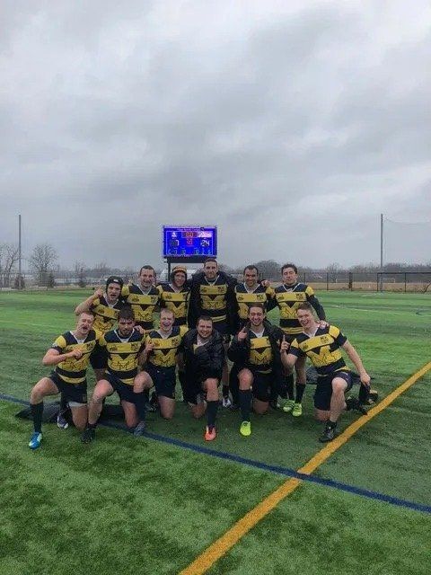 A group of rugby players are posing for a picture on a field.
