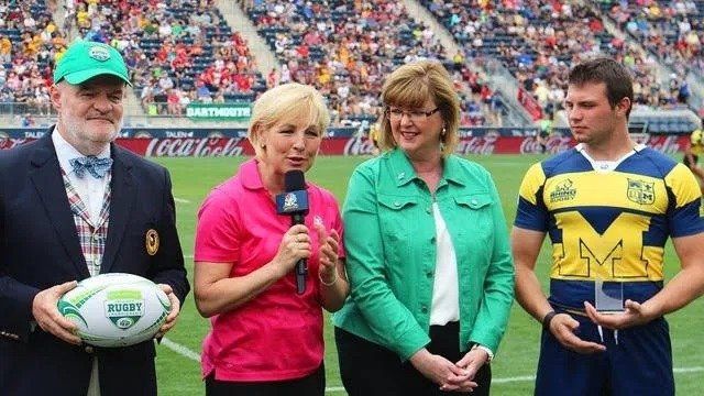 A group of people standing on a field holding a rugby ball