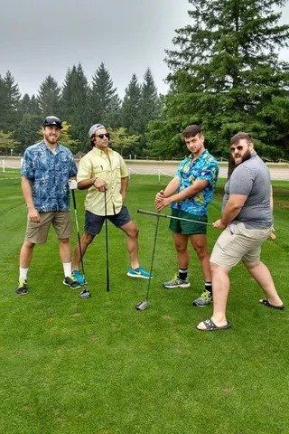 A group of men are standing on a golf course holding golf clubs.