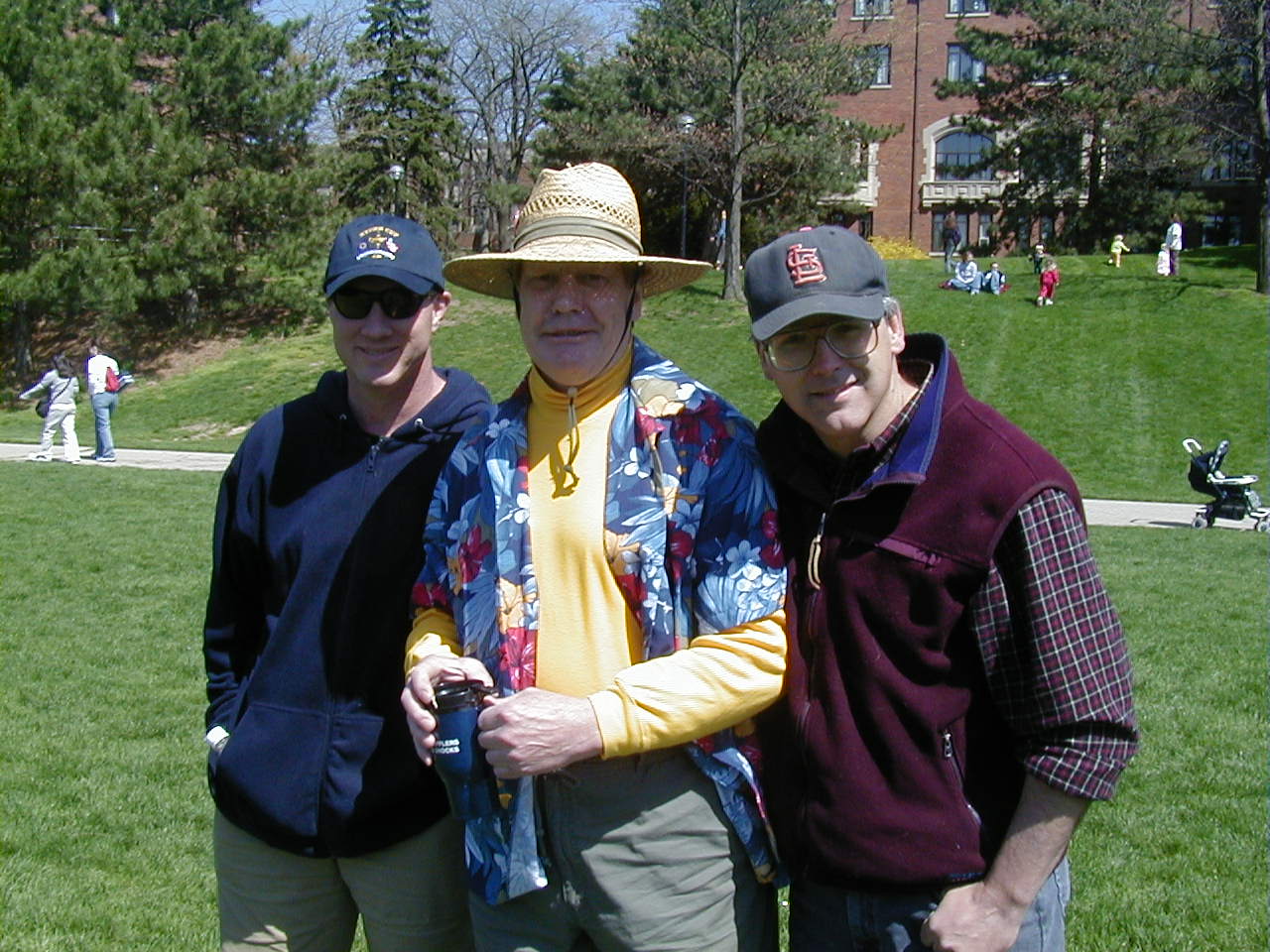 Three men posing for a picture with one wearing a hat with the letter b on it