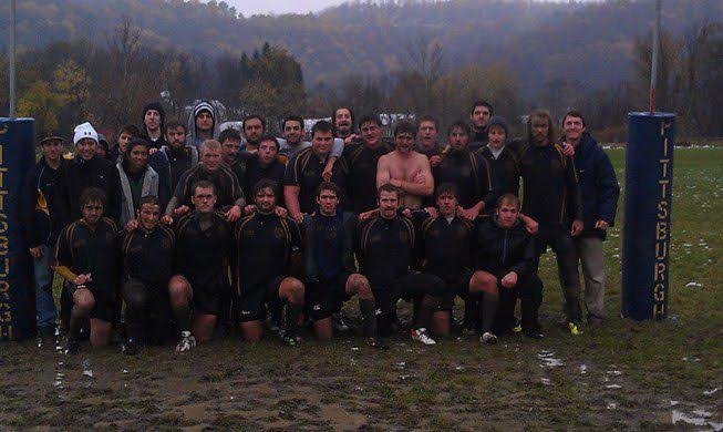A group of men are posing for a picture on a muddy field.