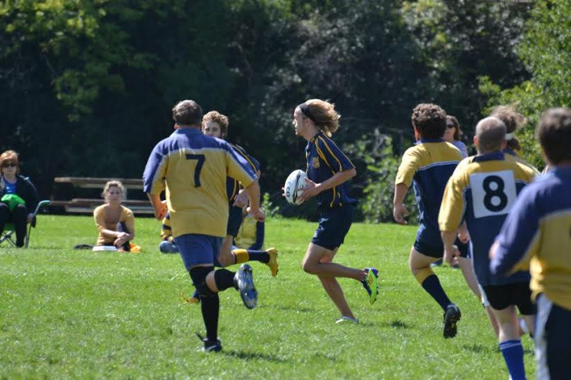 A group of boys are playing a game of rugby and one has the number 8 on his jersey