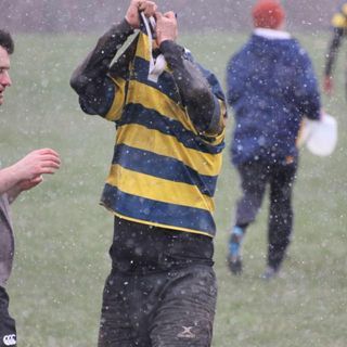 A man in a yellow and blue striped shirt is taking a picture