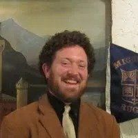 A man in a suit and tie is smiling in front of a painting.