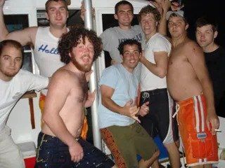 A group of men are posing for a picture and one of them is wearing a shirt that says hollis