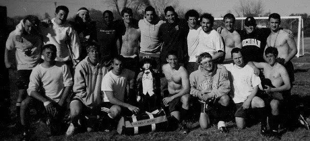 A group of men are posing for a picture and one of them is wearing a shirt that says columbia