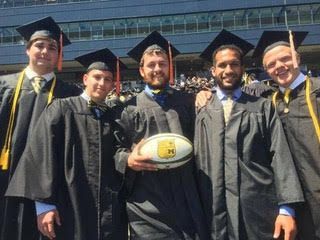 A group of graduates are posing for a picture and one of them is holding a rugby ball.