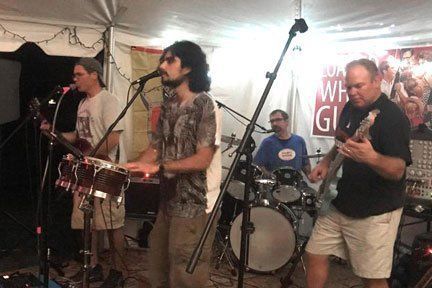 A group of men are playing instruments and singing into microphones on a stage.