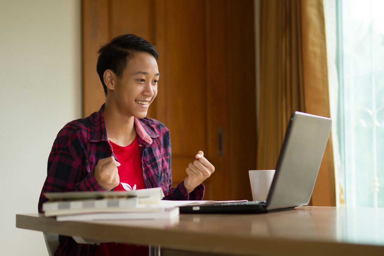 A man is sitting at a table using a laptop computer.