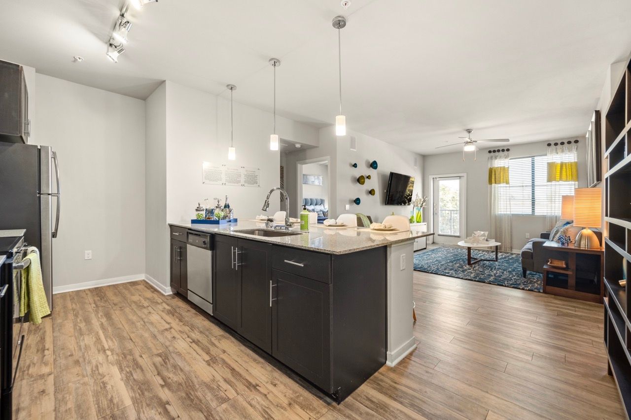 Open-concept kitchen with an island, dark cabinets, and a connected living area.