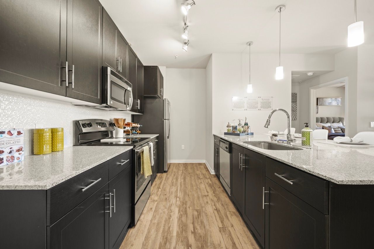 Modern kitchen with dark cabinets, stainless steel appliances, and an island.