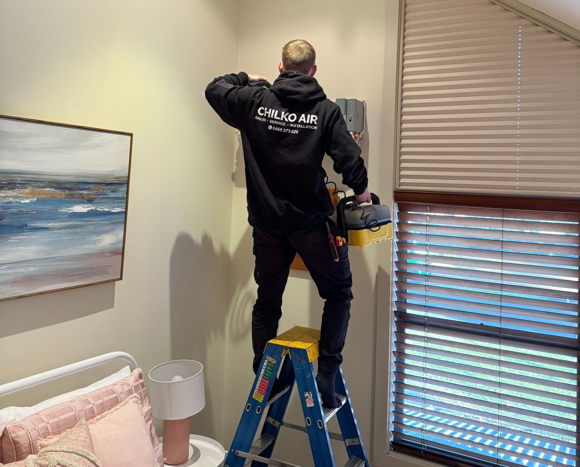 Chilko Air technician servicing a wall-mounted air conditioning unit in a residential setting