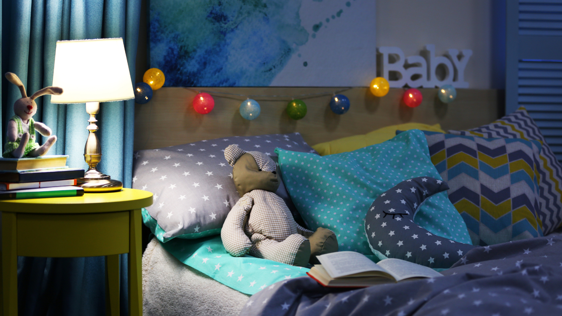 Cozy bedroom at night with a bed, lamp, stuffed animals, and string lights.