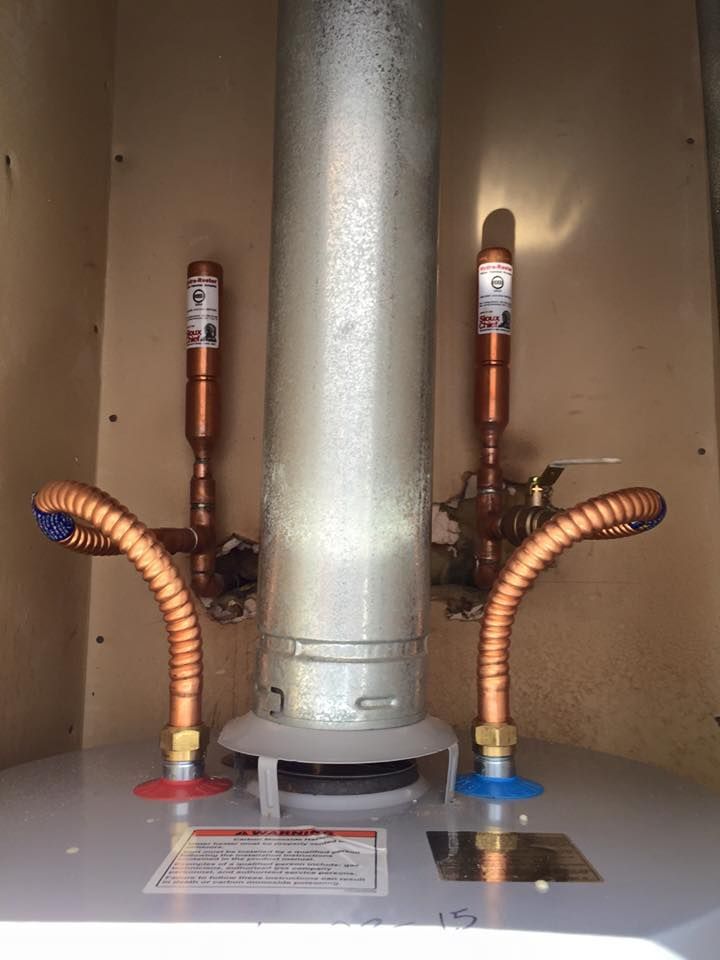 A close up of a water heater with copper pipes attached to it.