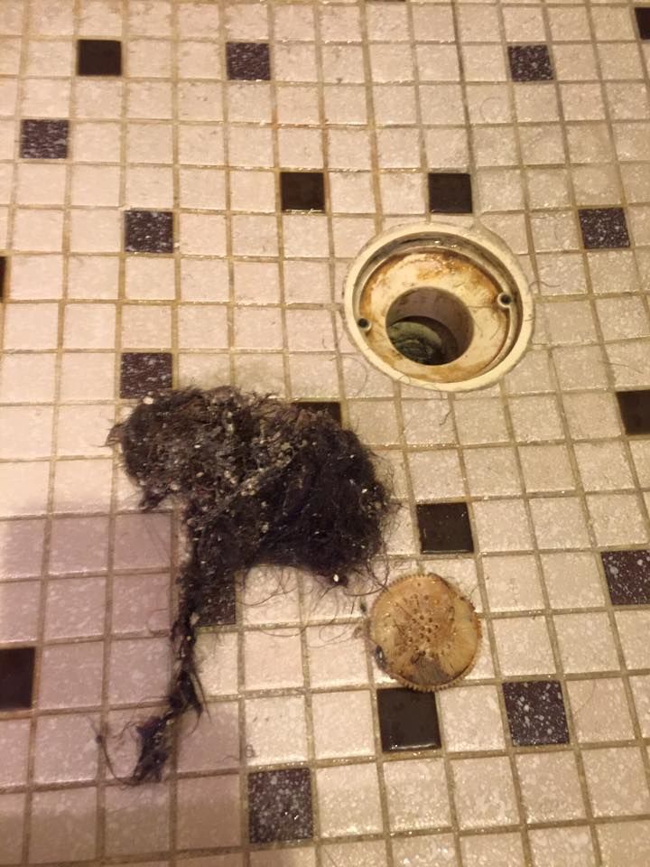 A close up of a drain on a tiled floor.