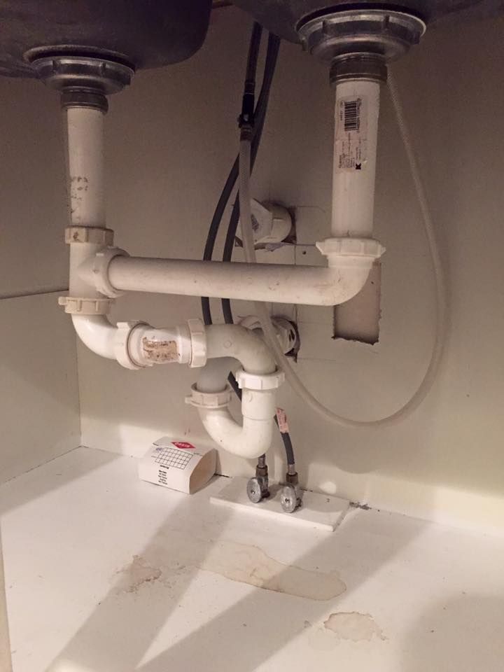 A sink with a lot of pipes underneath it.