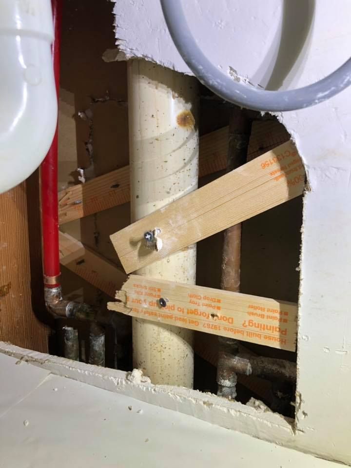 A pipe is being installed in a bathroom under a sink.