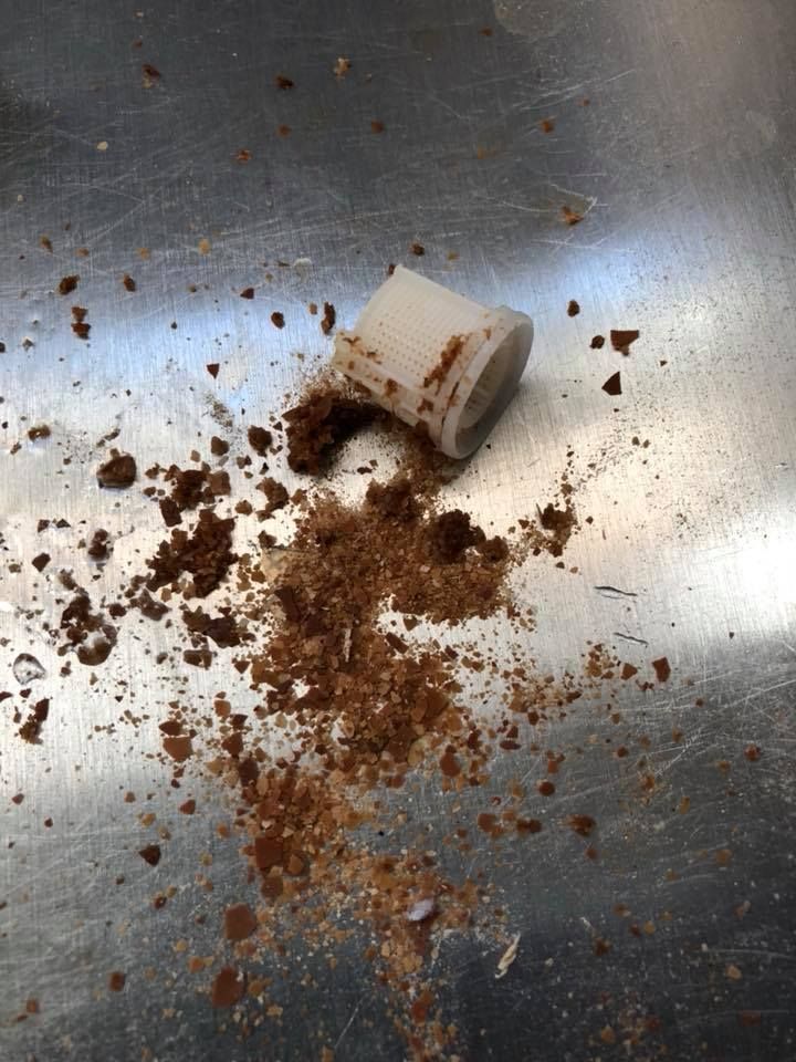 A piece of chocolate is laying on a metal surface.