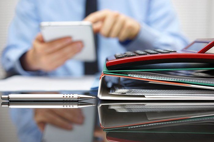 Man Holding A Tablet With Files And Calculator On The Table  — Outback Conveyancing Services in Alice Springs, NT