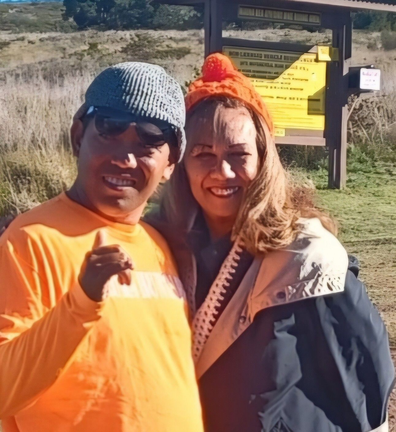 A man and a woman are posing for a picture in front of a sign