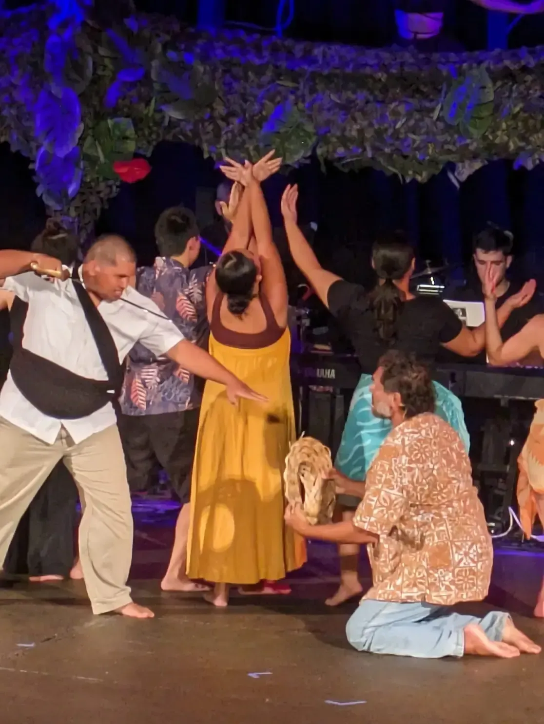 A group of people are dancing on a stage with their arms in the air