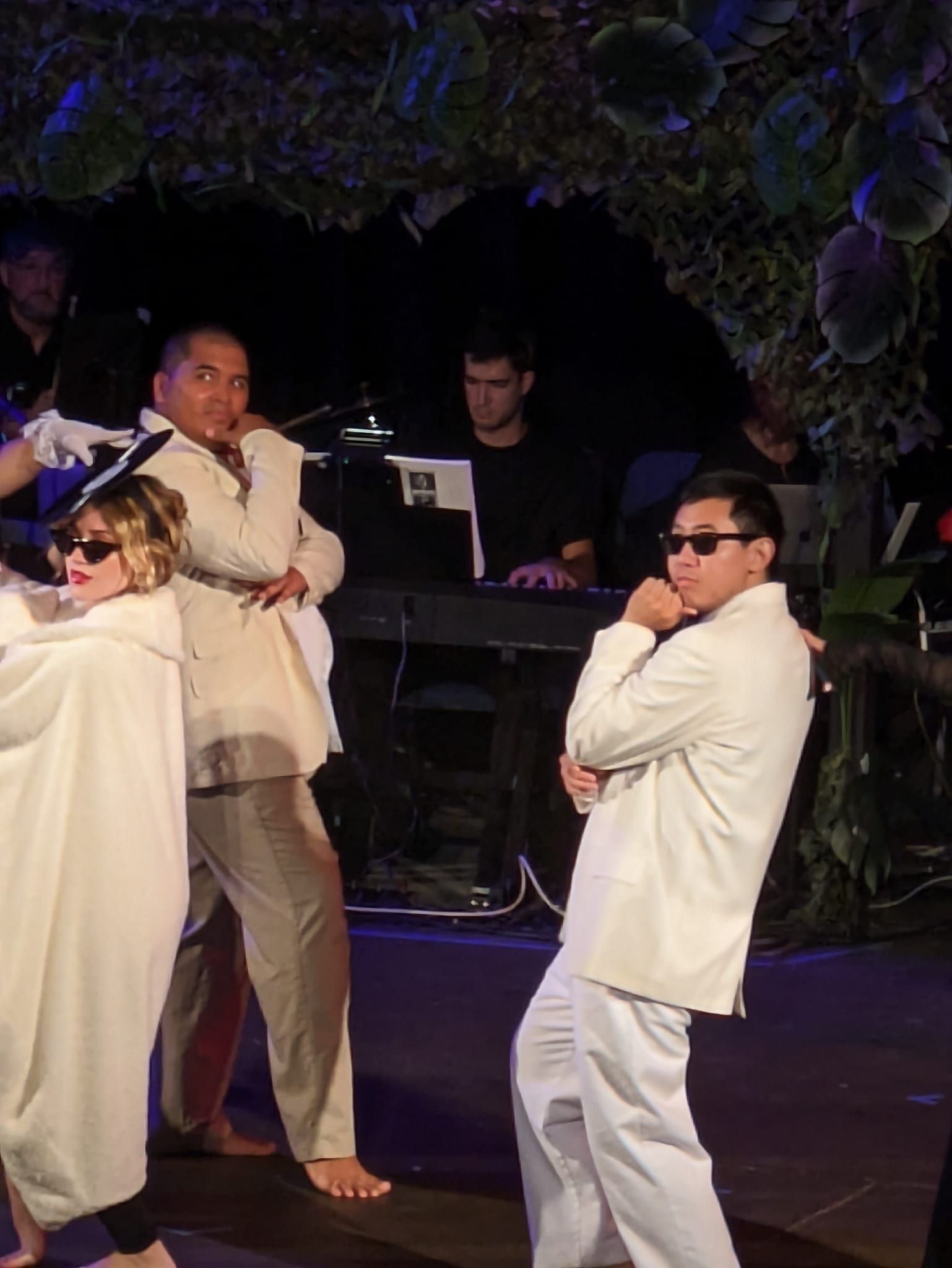 A group of people in white clothes are dancing on a stage