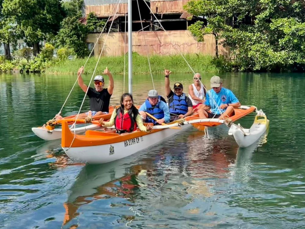 A group of people are sitting on a sailboat in the water.
