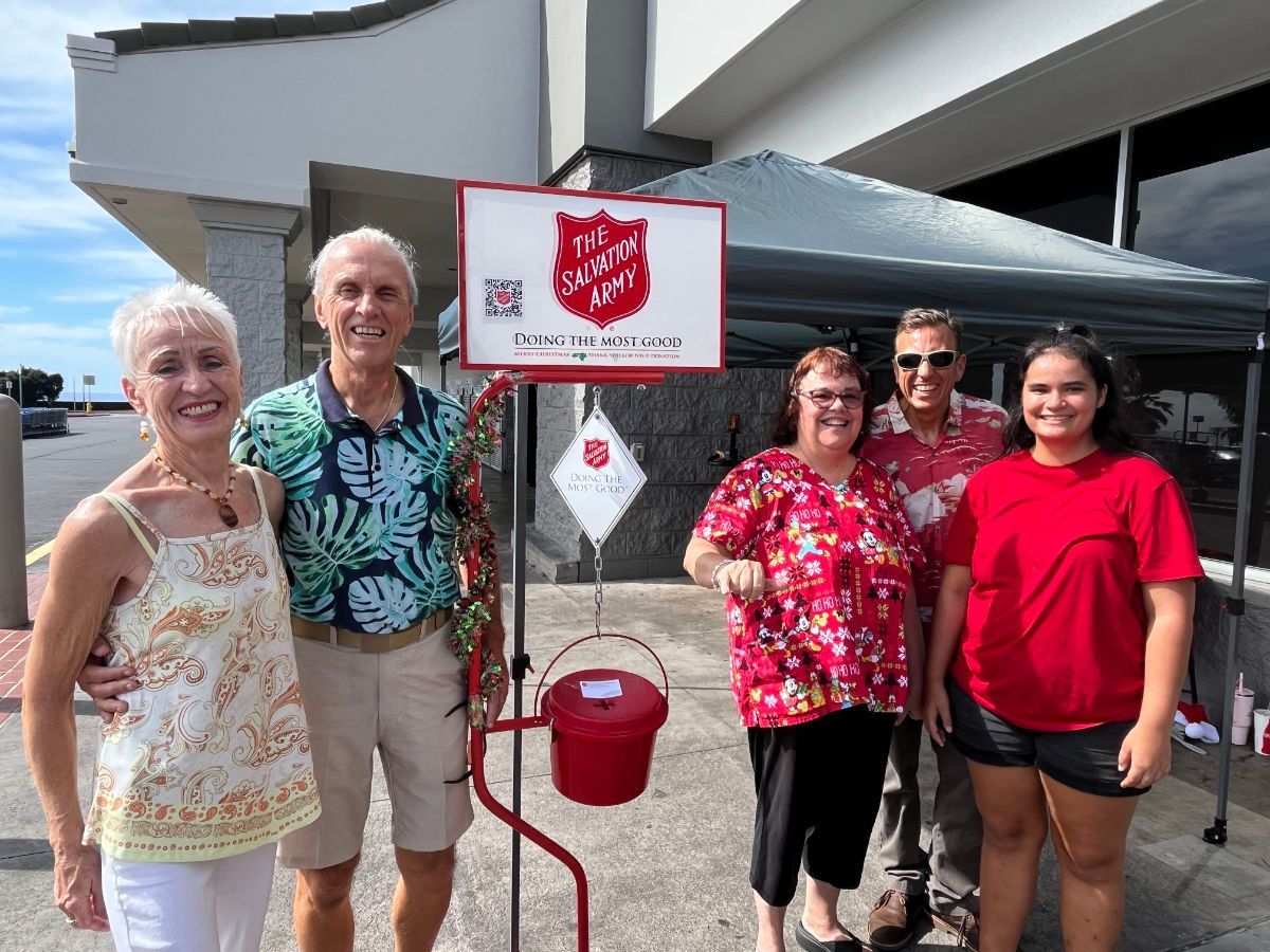 A group of people are standing in front of a salvation army sign.